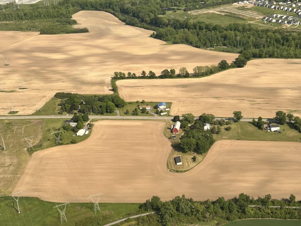 Rural farm fields, homes and a red barn from the air